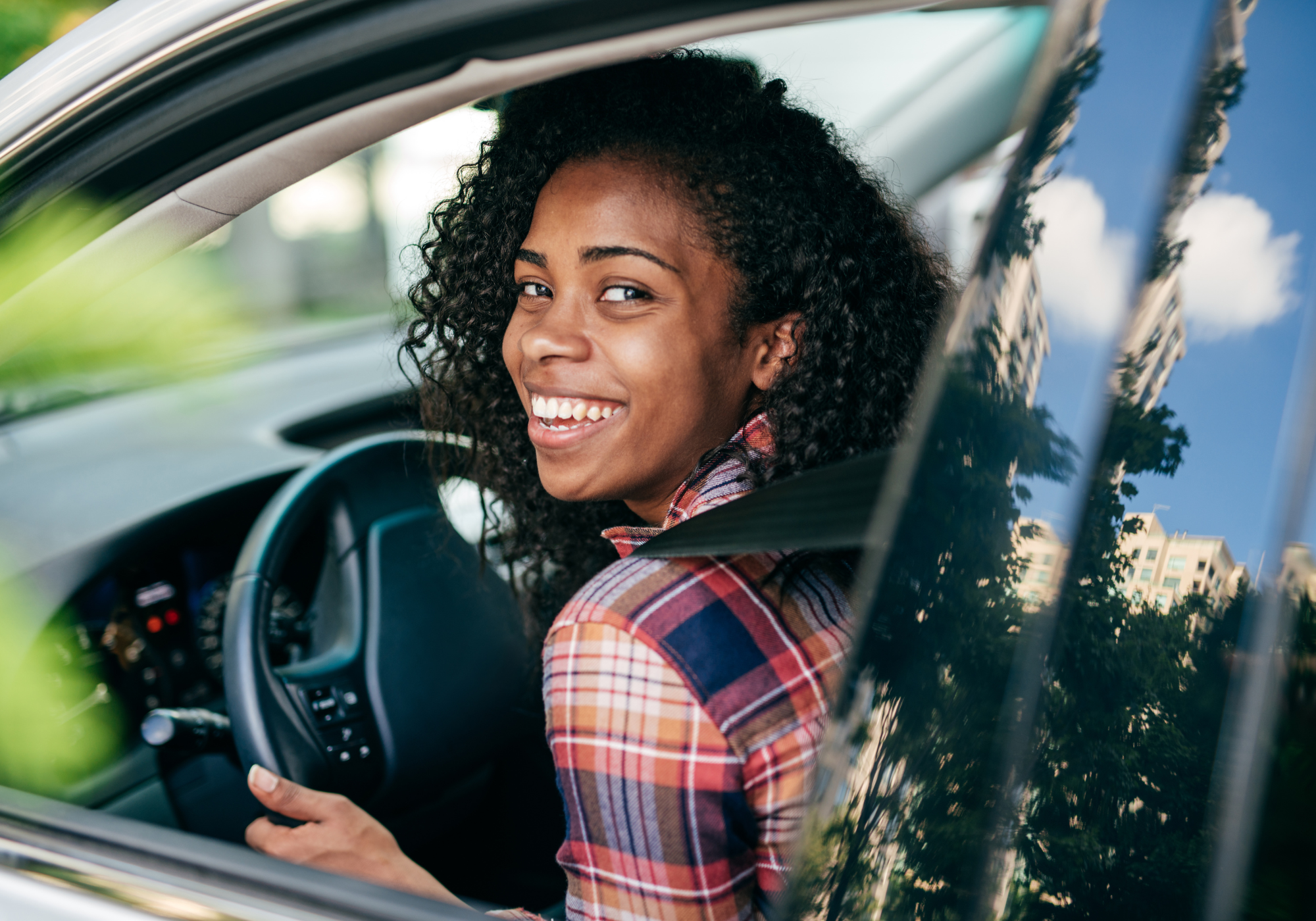 Smiling young woman driving new car.