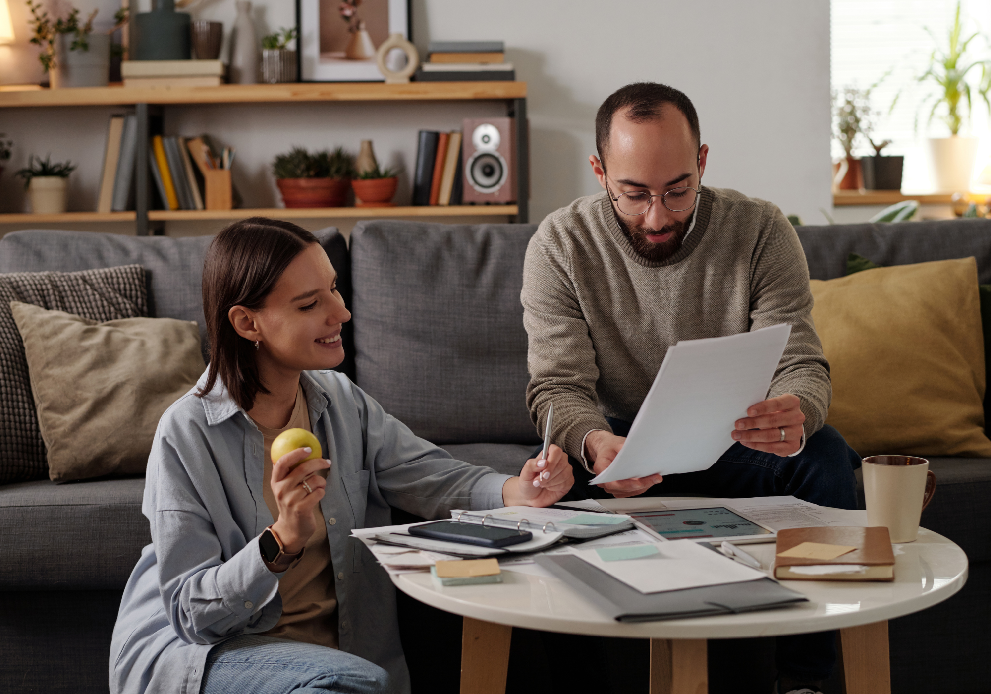 Couple sitting on a couch reviewing financial documents and discussing retirement planning together at home