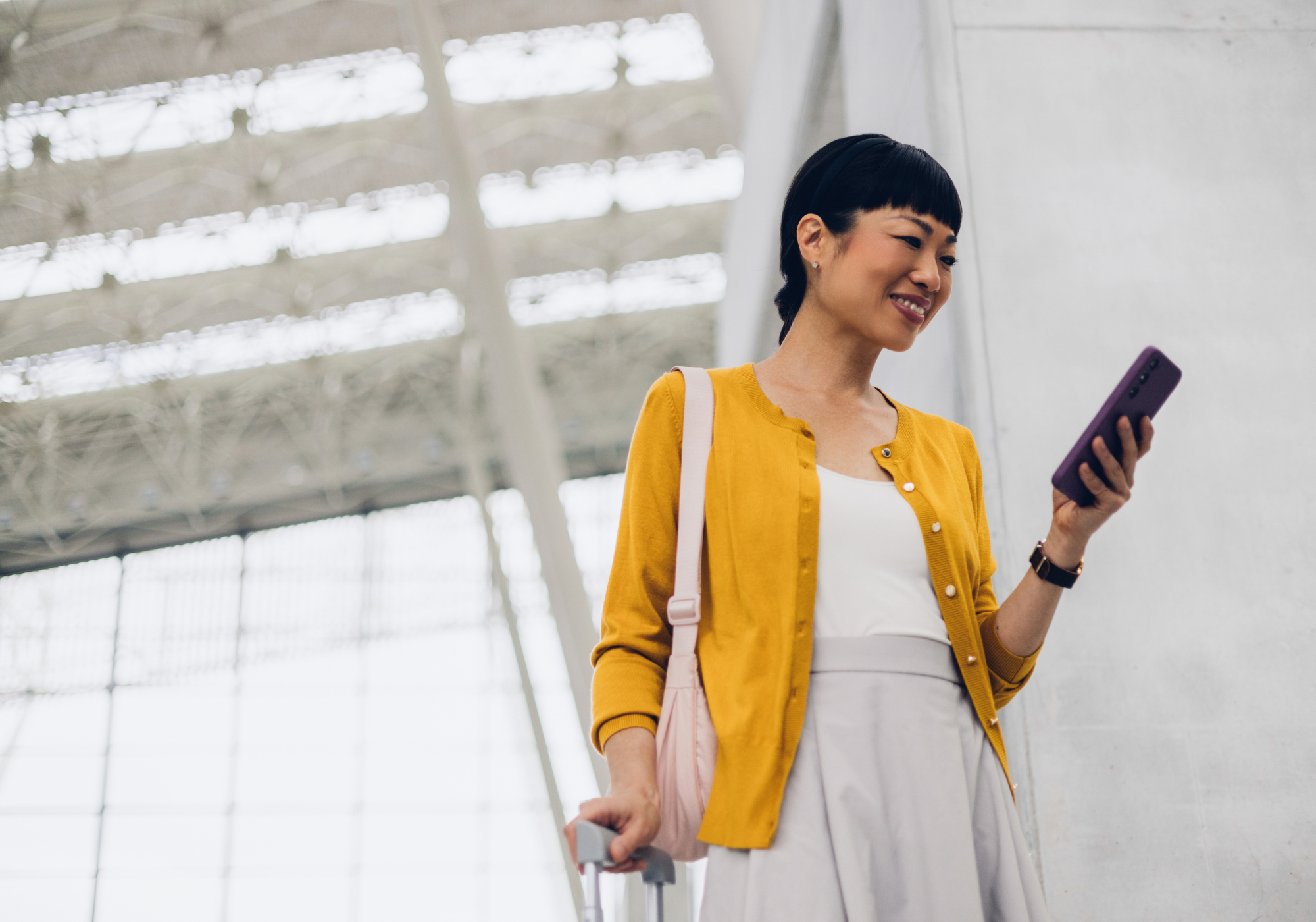 woman using The Police Credit Union's mobile banking app to review checking account while at the airport.