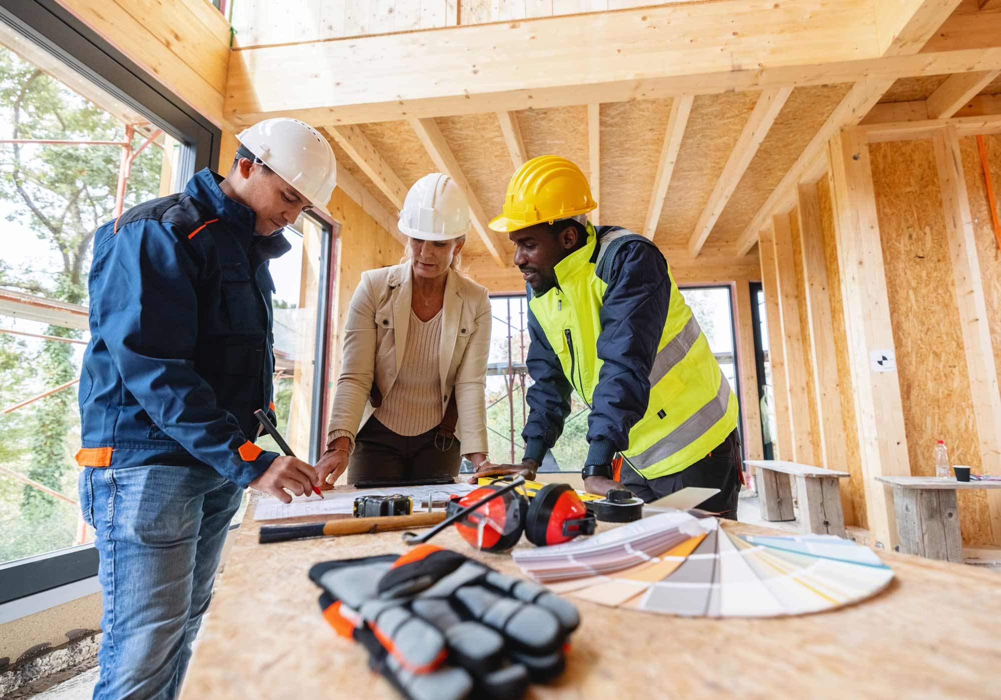 Construction team and homeowner reviewing blueprints on-site for a new home build.