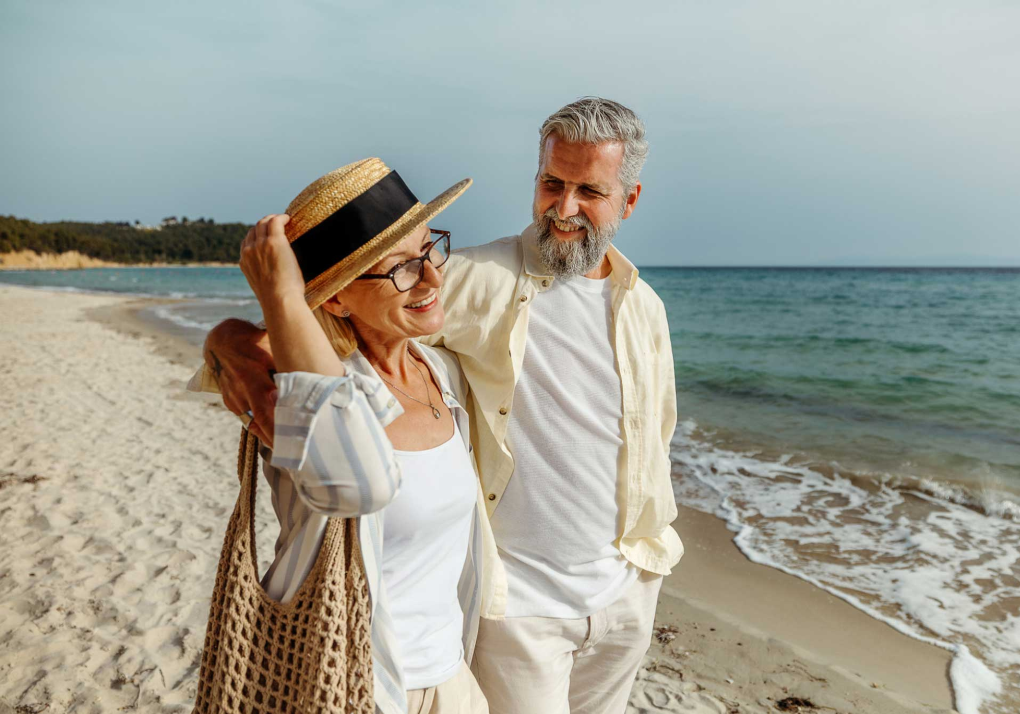 Retired couple happily walking along the beach.